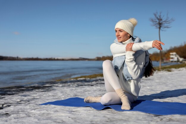 Mujer joven practicando yoga al aire libre durante el invierno en la playa