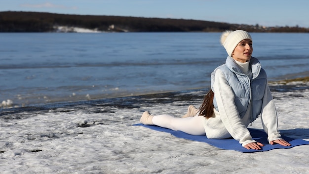 Foto gratuita mujer joven practicando yoga al aire libre durante el invierno en la playa