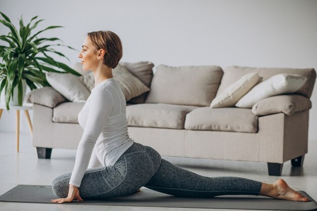 Mujer joven practicando yoga en casa en mat