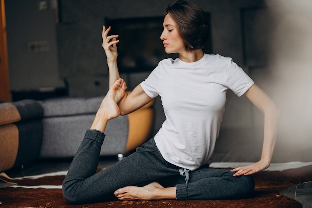 Mujer joven practicando yoga en casa