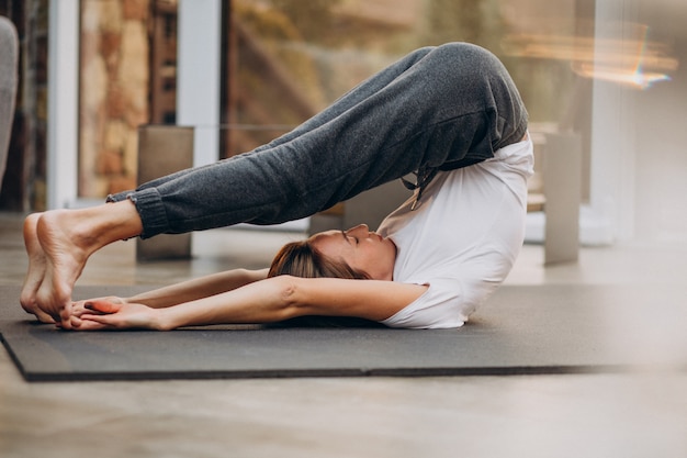 Mujer joven practicando yoga en casa