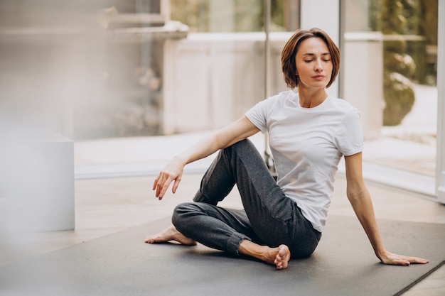 Mujer joven practicando yoga en casa