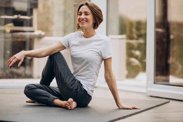 Mujer joven practicando yoga en casa