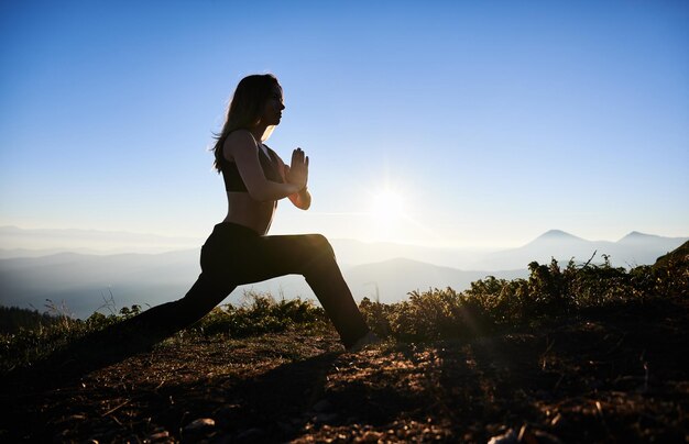 Mujer joven practicando yoga por la mañana en las montañas