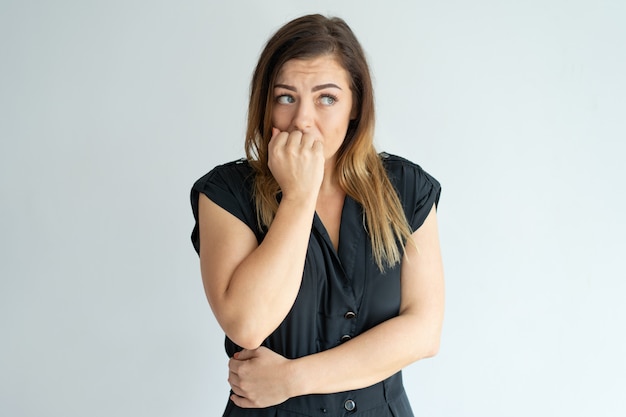 Mujer joven preocupada morderse las uñas mientras tiene ansiedad.