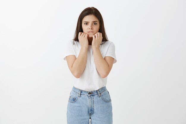 Mujer joven preocupada posando contra la pared blanca