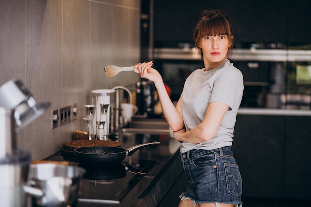 Mujer joven preparando el desayuno en la cocina por la mañana