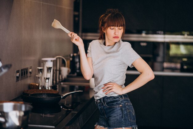 Mujer joven preparando el desayuno en la cocina por la mañana