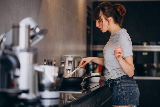 Mujer joven preparando el desayuno en la cocina por la mañana