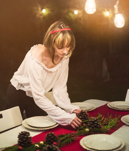 Mujer joven preparando la mesa para la cena de navidad