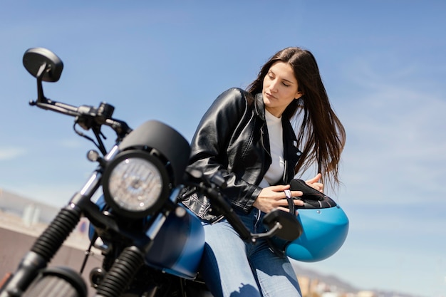 Mujer joven preparándose para andar en motocicleta en la ciudad