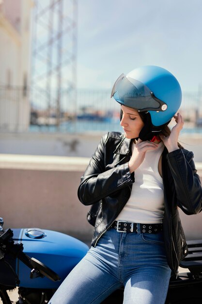 Mujer joven preparándose para andar en motocicleta en la ciudad