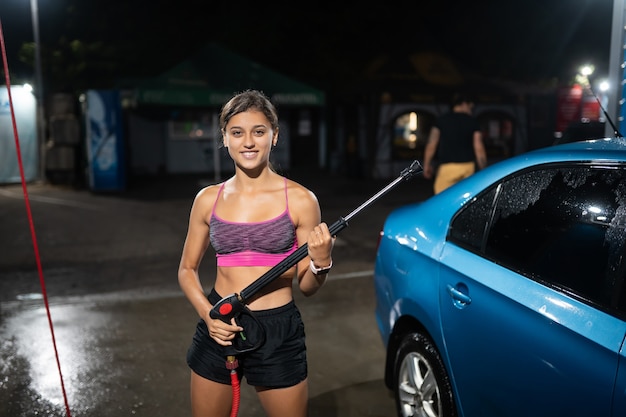 Mujer joven preparándose para la limpieza de automóviles en un lavado de autos