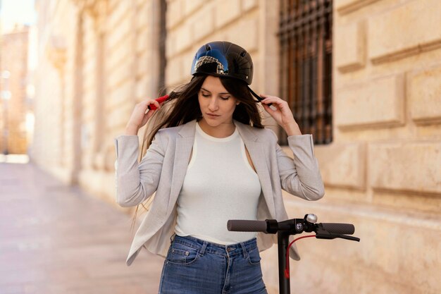 Mujer joven preparándose para viajar en un scooter eléctrico en la ciudad