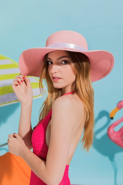 Mujer joven en la presentación rosada del sombrero y del traje de baño
