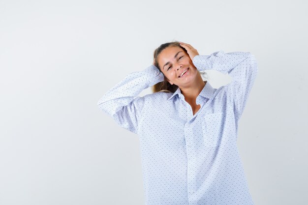 Mujer joven presionando las manos en los oídos, sonriendo con camisa blanca y mirando feliz