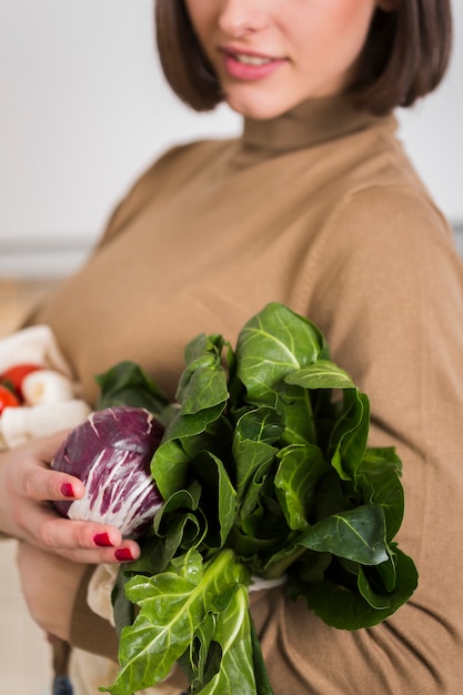 Mujer joven del primer que sostiene verduras frescas