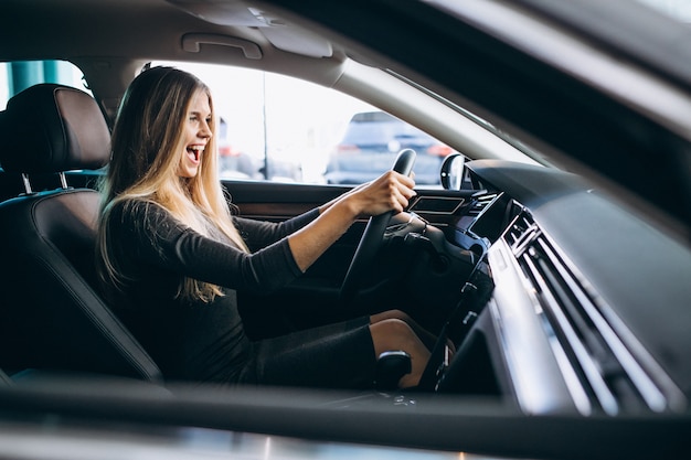 Mujer joven probando un automóvil desde una sala de exposición de automóviles