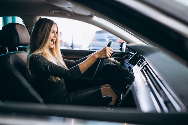 Mujer joven probando un automóvil desde una sala de exposición de automóviles