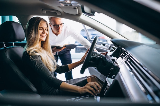 Mujer joven probando un automóvil desde una sala de exposición de automóviles