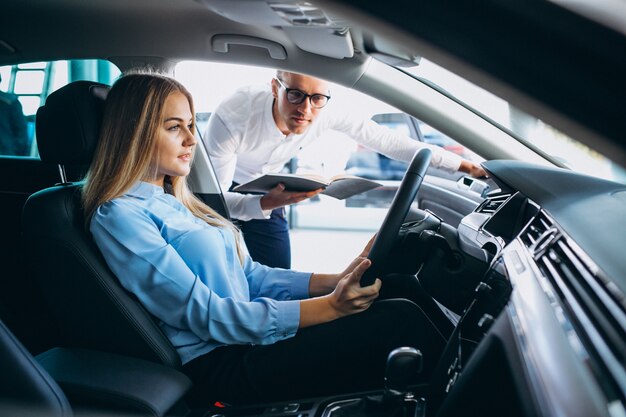 Mujer joven probando un automóvil desde una sala de exposición de automóviles