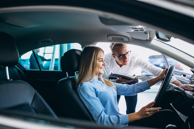 Mujer joven probando un automóvil desde una sala de exposición de automóviles