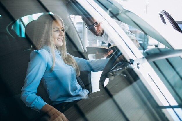 Mujer joven probando un automóvil desde una sala de exposición de automóviles