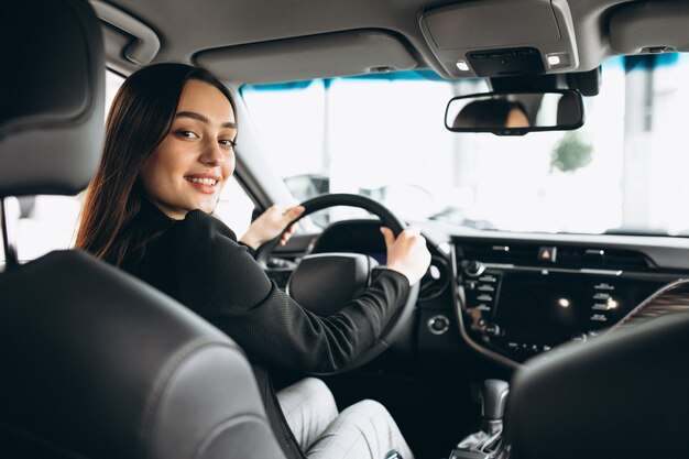 Mujer joven probando un automóvil en una sala de exposición de automóviles