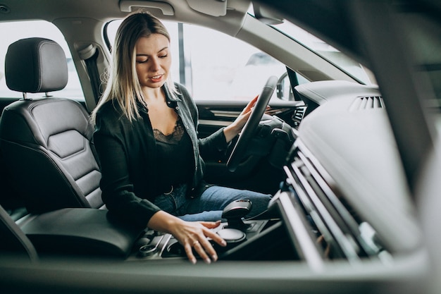 Foto gratuita mujer joven probando un automóvil en una sala de exposición de automóviles