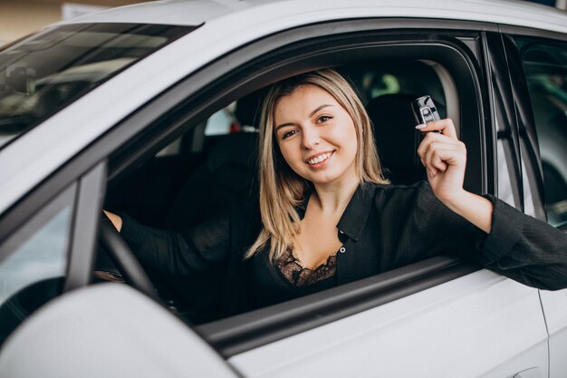 Mujer joven probando un automóvil en una sala de exposición de automóviles