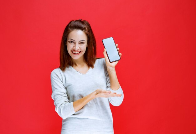 Mujer joven promocionando el nuevo modelo de una marca de teléfonos inteligentes