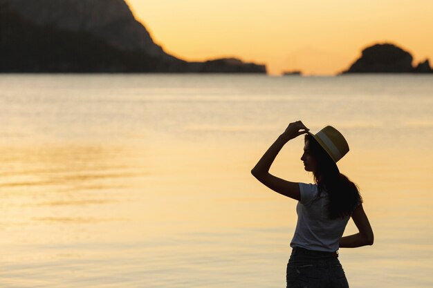 Mujer joven en puesta de sol en la orilla de un lago