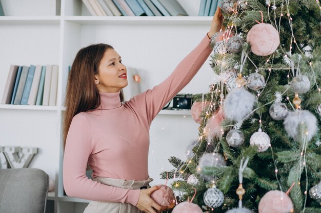 Mujer joven que adorna el árbol de navidad