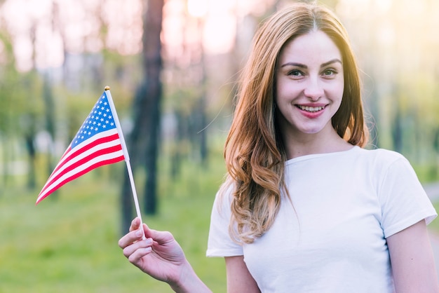 Mujer joven que agita la bandera de souvenirs de Estados Unidos