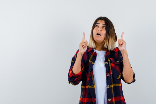 Mujer joven que aparece con los dedos sobre fondo blanco.