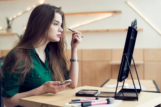 Mujer joven que aplica maquillaje