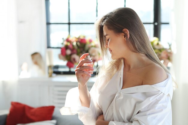 Mujer joven que aplica perfume.