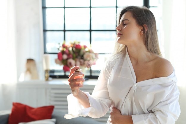 Mujer joven que aplica perfume.