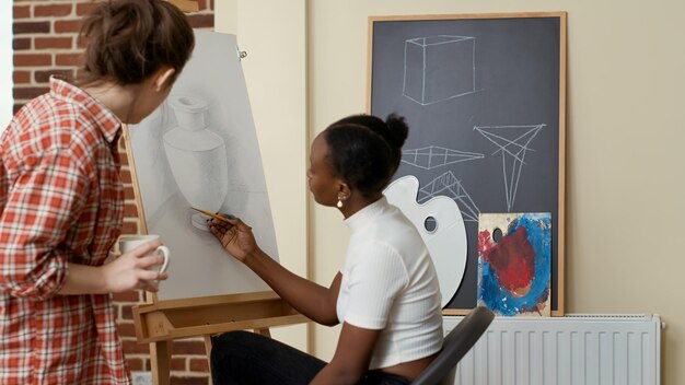 Mujer joven que asiste a la clase de arte para aprender habilidades de dibujo de la artista femenina, usando lápiz para dibujar el modelo de inspiración. Práctica de taller para dibujar diseño de obras de arte. Disparo de trípode.