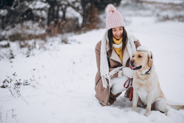 Mujer joven que camina con su perro en un parque de invierno