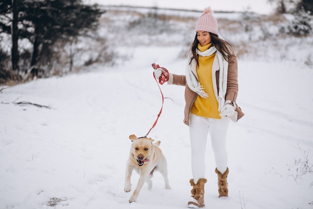 Mujer joven que camina con su perro en un parque de invierno