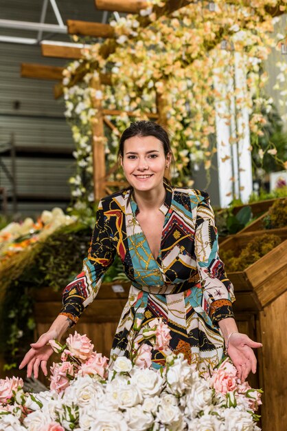 Mujer joven que se coloca cerca de las flores color de rosa