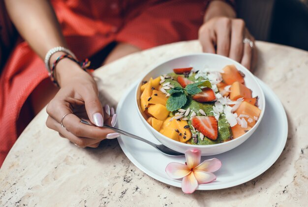 Mujer joven que come el batido en la cafetería, retrato feliz al aire libre