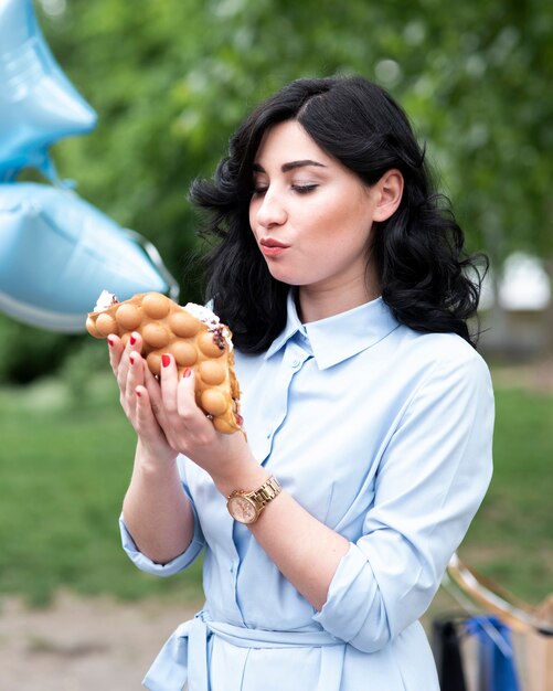 Mujer joven que come una burbuja waffle