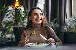 Foto gratuita mujer joven que come la ensalada en un café