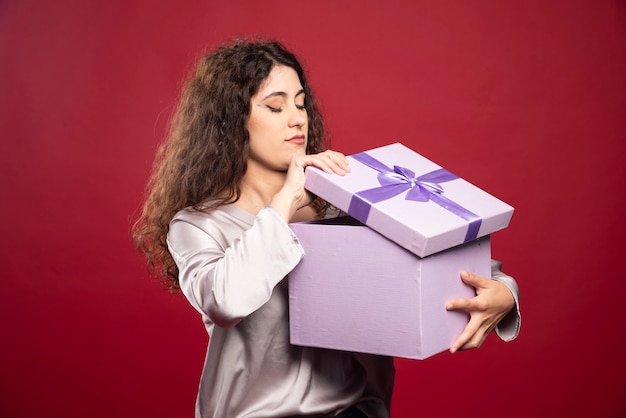 Mujer joven que controla la caja de regalo púrpura.