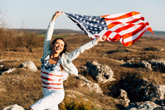 Foto gratuita mujer joven que corre con banderas americanas que agitan