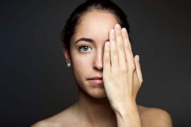 Mujer joven que cubre la mitad de su cara con una mano.