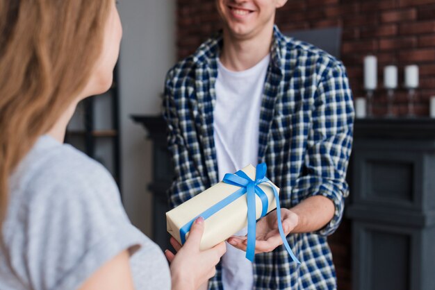 Mujer joven que da el regalo al marido