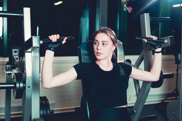 Mujer joven que ejercita en gimnasio